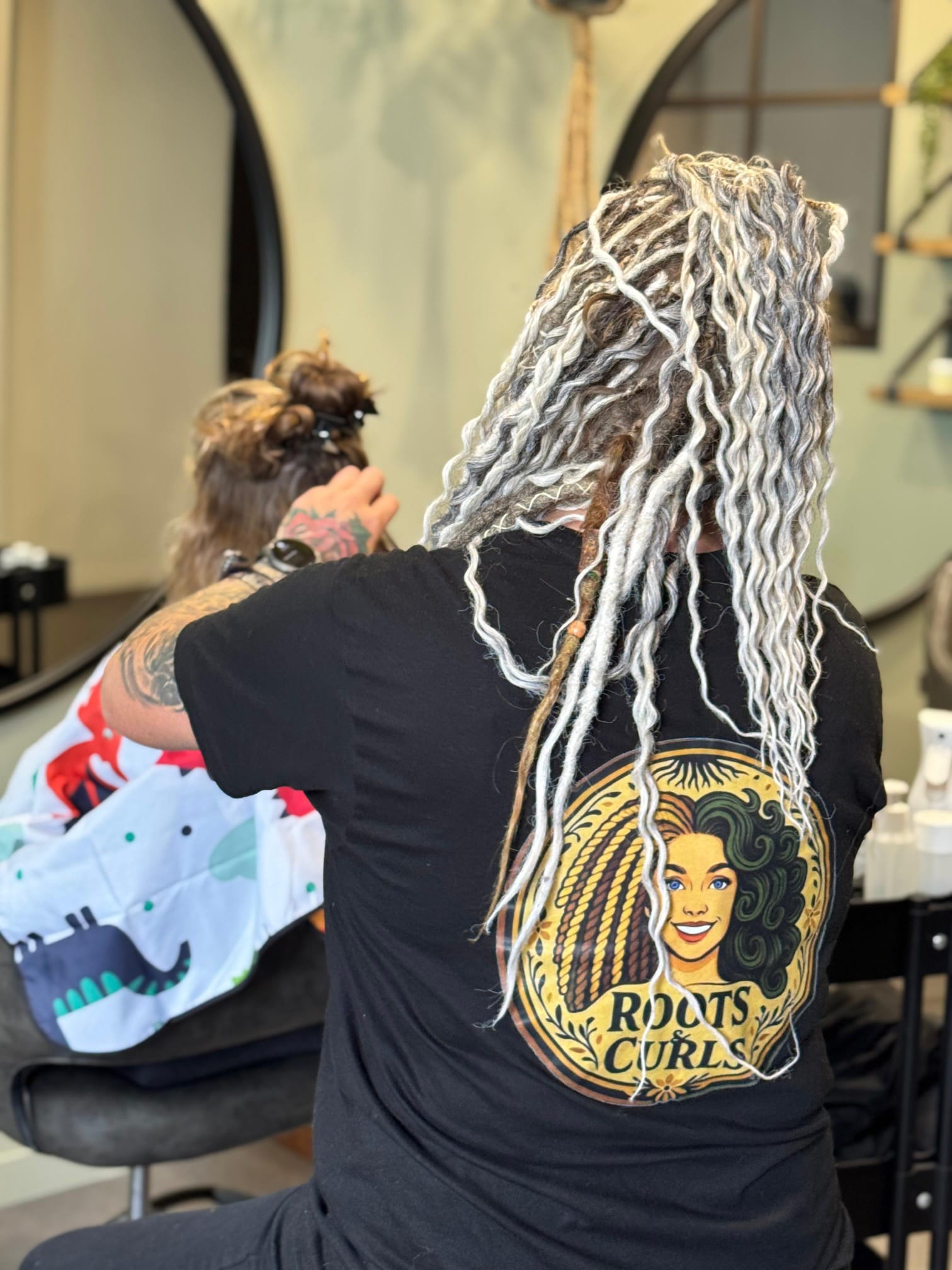 Christine aan het werk bij een klant, met het Roots & Curls logo op haar shirt